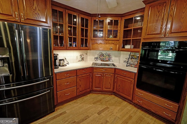 4393 Cannon Rd, Loganville, GA 30052 - kitchen with black appliances, light wood finished floors, backsplash, light countertops, and glass insert cabinets