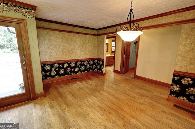 4393 Cannon Rd, Loganville, GA 30052 - unfurnished dining area featuring light wood-style flooring, wallpapered walls, ornamental molding, and a textured ceiling