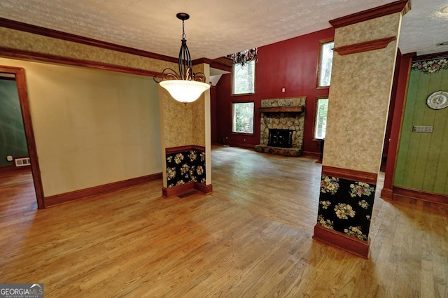 4393 Cannon Rd, Loganville, GA 30052 - unfurnished dining area with a textured ceiling, wood finished floors, a stone fireplace, and ornamental molding