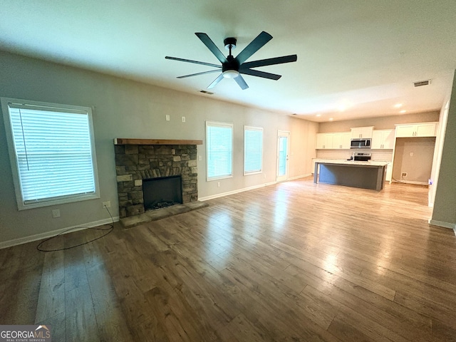 248 Webster Lake Dr, Temple, GA 30179 - unfurnished living room with light wood-style floors, a ceiling fan, and a stone fireplace