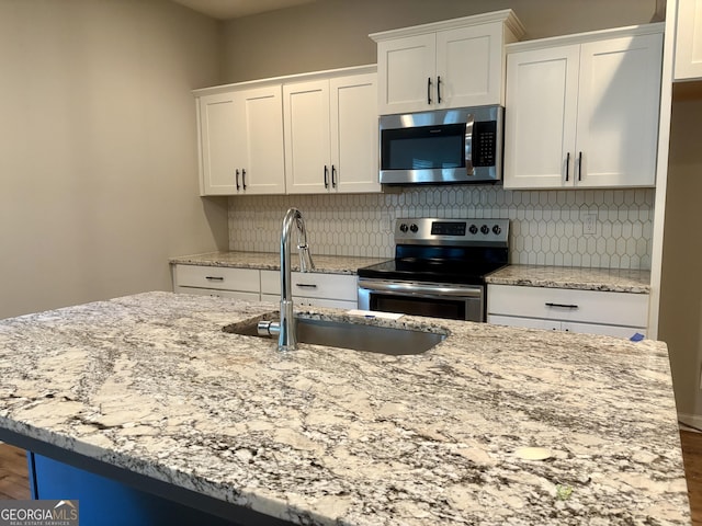 248 Webster Lake Dr, Temple, GA 30179 - kitchen with appliances with stainless steel finishes, white cabinetry, tasteful backsplash, and light stone counters