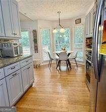 507 Legacy Park Ln, Powder Springs, GA 30127 - kitchen featuring freestanding refrigerator, hanging light fixtures, gray cabinetry, and stone countertops