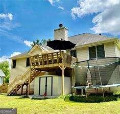 507 Legacy Park Ln, Powder Springs, GA 30127 - rear view of property featuring stairway, a deck, a shed, a yard, and a trampoline