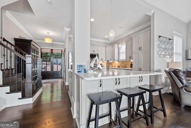 202 Jackson Rd SE, Milledgeville, GA 31061 - kitchen featuring backsplash, dark wood-type flooring, light countertops, stainless steel microwave, and a breakfast bar