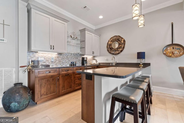 202 Jackson Rd SE, Milledgeville, GA 31061 - kitchen with dark countertops, a kitchen bar, tasteful backsplash, ornamental molding, and decorative light fixtures