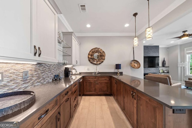 202 Jackson Rd SE, Milledgeville, GA 31061 - kitchen with dark countertops, tasteful backsplash, a peninsula, light wood finished floors, and crown molding