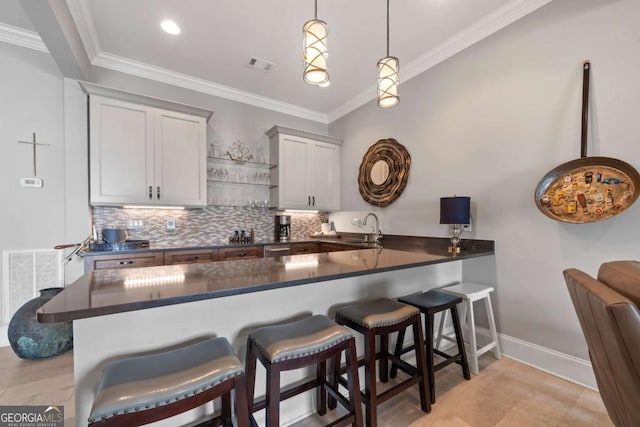 202 Jackson Rd SE, Milledgeville, GA 31061 - kitchen with dark countertops, backsplash, crown molding, a breakfast bar area, and a peninsula