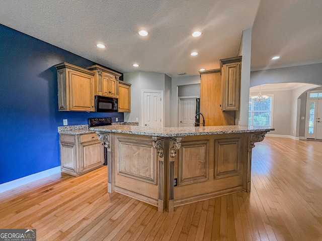 152 Huron Loop, Brunswick, GA 31523 - kitchen featuring black microwave, arched walkways, a breakfast bar area, light wood-style flooring, and light stone countertops