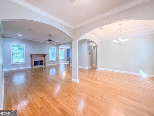 152 Huron Loop, Brunswick, GA 31523 - unfurnished living room featuring light wood-style floors, a fireplace, ceiling fan, arched walkways, and a chandelier
