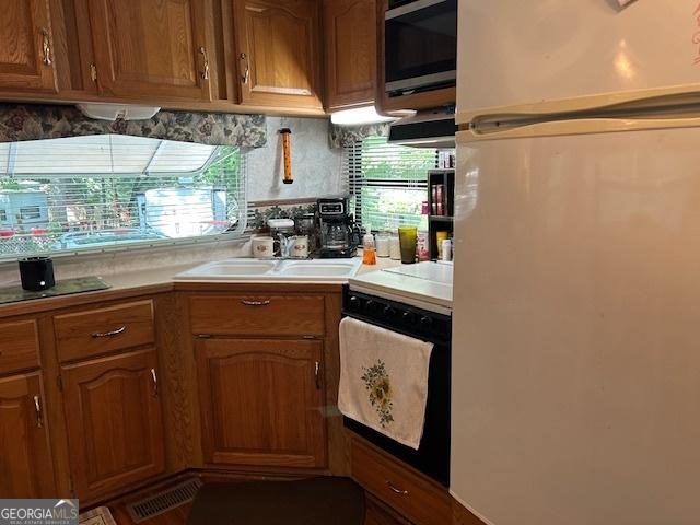 39 Terrace Cir, Cleveland, GA 30528 - kitchen featuring black appliances, light countertops, brown cabinetry, and decorative backsplash