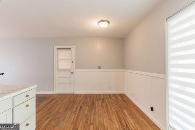 1784 Treymire Ct, Stone Mountain, GA 30088 - unfurnished dining area with wood-type flooring, a wainscoted wall, and healthy amount of natural light