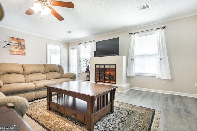 105 Shadow Ln, Warner Robins, GA 31088 - living area featuring a tiled fireplace, wood finished floors, crown molding, a ceiling fan, and a textured ceiling