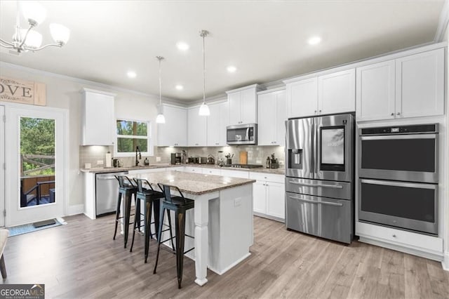 349 Garnet Dr, Acworth, GA 30101 - kitchen with appliances with stainless steel finishes, light wood-style floors, white cabinets, a kitchen breakfast bar, and ornamental molding