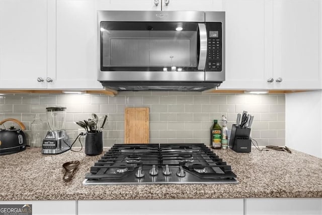349 Garnet Dr, Acworth, GA 30101 - kitchen featuring appliances with stainless steel finishes, white cabinetry, light stone countertops, and tasteful backsplash