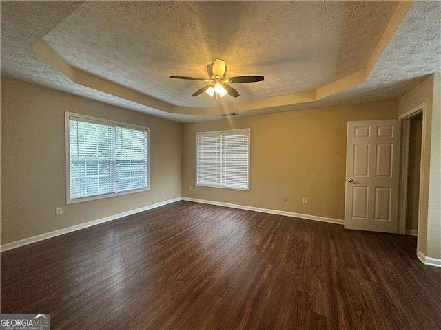 4189 Duncan Ives Dr, Buford, GA 30519 - empty room with a tray ceiling, dark wood-style floors, a textured ceiling, a ceiling fan, and healthy amount of natural light
