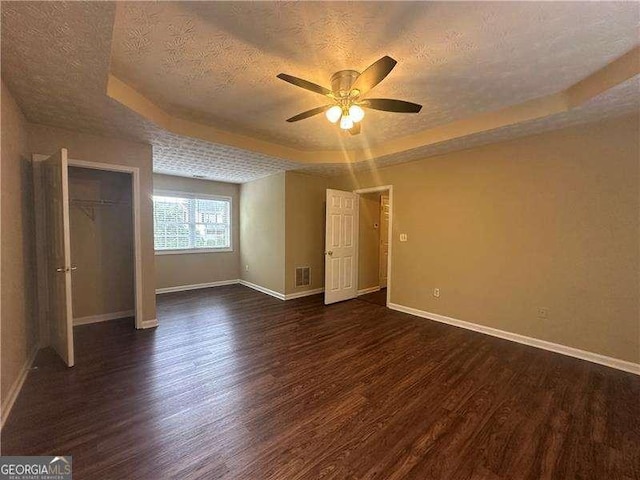 4189 Duncan Ives Dr, Buford, GA 30519 - unfurnished bedroom featuring a raised ceiling, dark wood-type flooring, a textured ceiling, a closet, and a ceiling fan