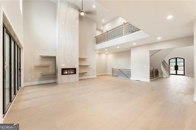 15792 Thompson Rd, Milton, GA 30004 - unfurnished living room with a high ceiling, a large fireplace, recessed lighting, wood finished floors, and stairway