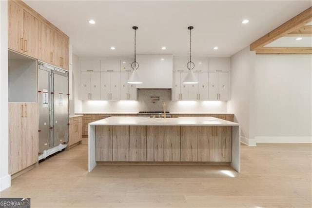 15792 Thompson Rd, Milton, GA 30004 - kitchen with light brown cabinetry, a large island with sink, light wood finished floors, recessed lighting, and light countertops