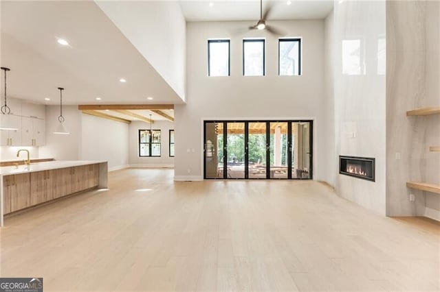 15792 Thompson Rd, Milton, GA 30004 - unfurnished living room with a high ceiling, a ceiling fan, a glass covered fireplace, light wood-type flooring, and recessed lighting
