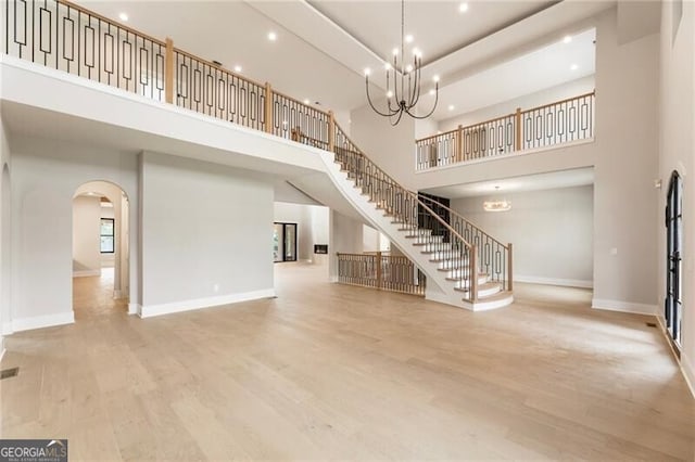 15792 Thompson Rd, Milton, GA 30004 - unfurnished living room with a towering ceiling, arched walkways, wood finished floors, recessed lighting, and a chandelier