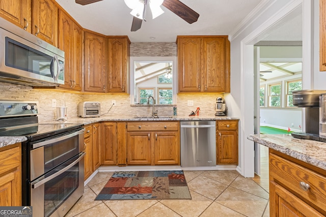 2421 Pittman Cir, Cumming, GA 30040 - kitchen with appliances with stainless steel finishes, a ceiling fan, decorative backsplash, and light stone countertops