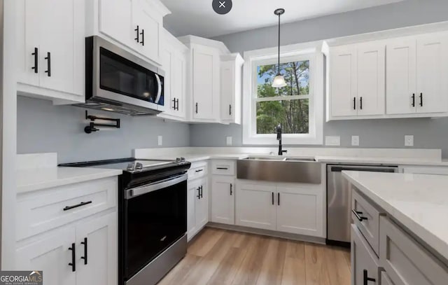 0 Nocona Trl, Ellijay, GA 30536 - kitchen with appliances with stainless steel finishes, light wood-type flooring, light countertops, hanging light fixtures, and white cabinetry