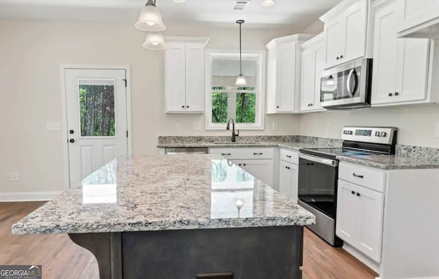 0 Nocona Trl, Ellijay, GA 30536 - kitchen featuring stainless steel appliances, a kitchen island, wood finished floors, white cabinetry, and light stone counters