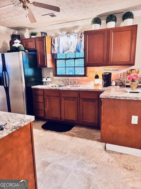 791 Bristol Way, Lithonia, GA 30058 - kitchen featuring freestanding refrigerator, crown molding, ceiling fan, light stone countertops, and brown cabinets