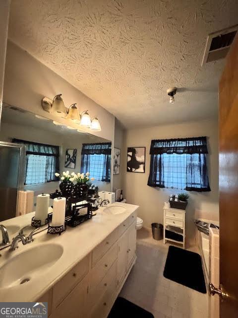 791 Bristol Way, Lithonia, GA 30058 - bathroom with a textured ceiling, double vanity, and a stall shower