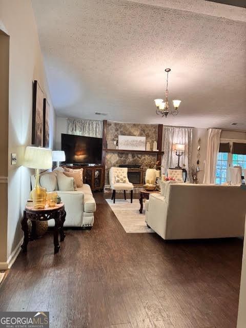 791 Bristol Way, Lithonia, GA 30058 - living room with hardwood / wood-style floors, a textured ceiling, a chandelier, and a stone fireplace