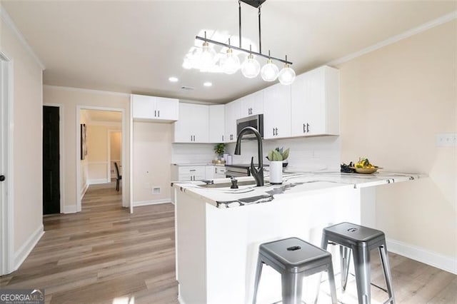 300 Saddle Creek Ln, Roswell, GA 30076 - kitchen featuring stainless steel microwave, a peninsula, light wood-style flooring, light countertops, and a kitchen bar