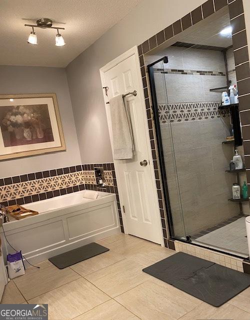 201 William D Evans Ct, Kathleen, GA 31047 - bathroom featuring tile patterned floors, a garden tub, a stall shower, tile walls, and a wainscoted wall
