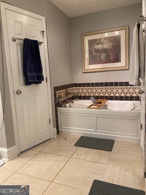 201 William D Evans Ct, Kathleen, GA 31047 - bathroom featuring a garden tub, tile walls, tile patterned flooring, and a wainscoted wall