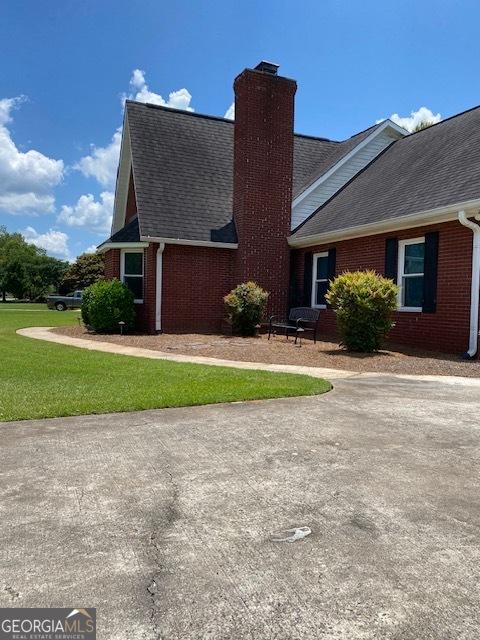 201 William D Evans Ct, Kathleen, GA 31047 - view of property exterior with brick siding, a chimney, roof with shingles, and a yard
