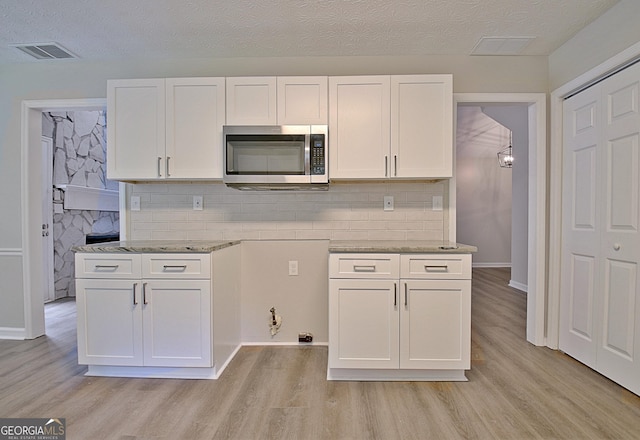 85 Holly Springs Rd, Sharpsburg, GA 30277 - kitchen with stainless steel microwave, white cabinetry, light wood-style flooring, and a textured ceiling