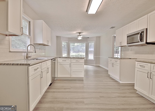 85 Holly Springs Rd, Sharpsburg, GA 30277 - kitchen with stainless steel appliances, a textured ceiling, a peninsula, light stone counters, and a ceiling fan