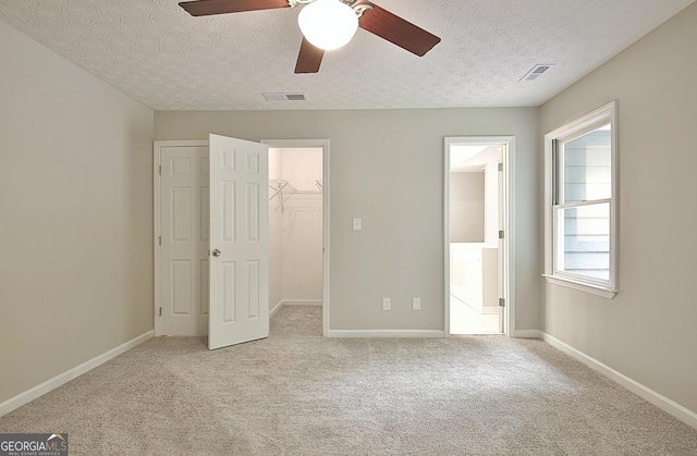 85 Holly Springs Rd, Sharpsburg, GA 30277 - unfurnished bedroom with a walk in closet, carpet flooring, a textured ceiling, a closet, and connected bathroom