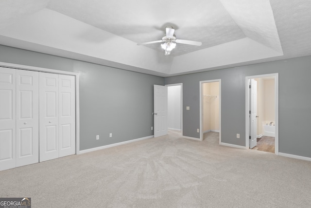 120 Bramble Bush Trl, Covington, GA 30014 - unfurnished bedroom featuring a tray ceiling, carpet flooring, a closet, ensuite bath, and a ceiling fan