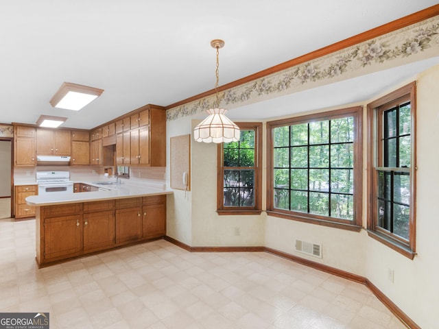 25 Ridgeview Dr, Jonesboro, GA 30236 - kitchen with under cabinet range hood, stove, light countertops, a peninsula, and brown cabinets