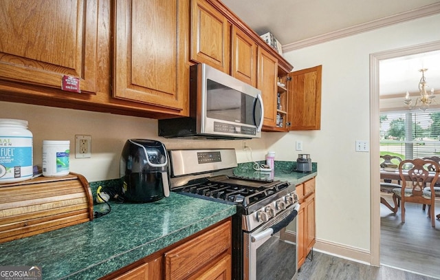 3514 Blackberry, Conyers, GA 30094 - kitchen with appliances with stainless steel finishes, wood finished floors, ornamental molding, brown cabinetry, and a chandelier