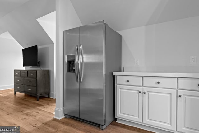 1230 Lake Club Dr, Greensboro, GA 30642 - kitchen with stainless steel fridge with ice dispenser, white cabinetry, light wood-type flooring, vaulted ceiling, and light countertops