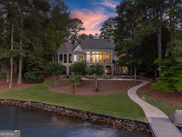 1230 Lake Club Dr, Greensboro, GA 30642 - back of property at dusk with a lawn, a water view, a sunroom, and stone siding