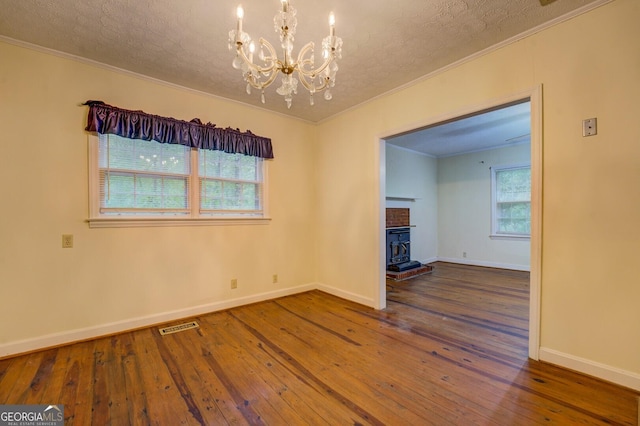 6111 Old Monticello St SE, Covington, GA 30014 - spare room featuring ornamental molding, hardwood / wood-style flooring, a chandelier, a textured ceiling, and a wood stove