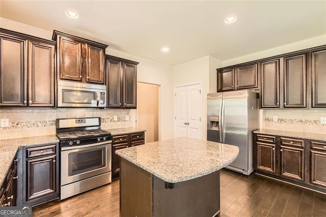 219 Sleepy Way, Canton, GA 30114 - kitchen featuring appliances with stainless steel finishes, dark brown cabinets, dark wood-type flooring, light stone counters, and a kitchen island