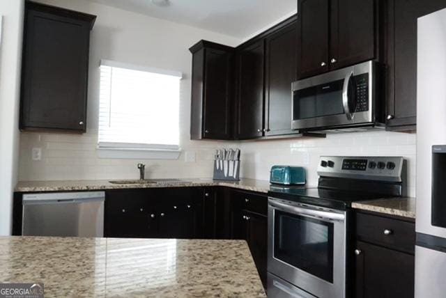 11096 Cornerstone Way, Hampton, GA 30228 - kitchen featuring stainless steel appliances, backsplash, light stone countertops, and dark cabinets