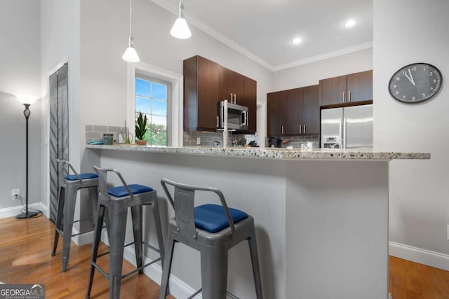 1903 Anjaco Rd NW Unit 5, Atlanta, GA 30309 - kitchen featuring appliances with stainless steel finishes, a kitchen bar, decorative backsplash, ornamental molding, and recessed lighting