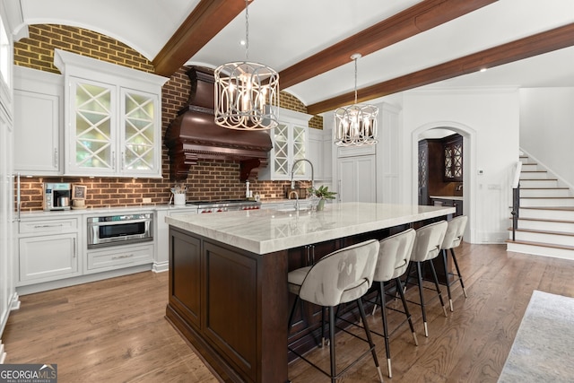 4874 Kettle River Pt, Suwanee, GA 30024 - kitchen featuring a chandelier, white cabinets, light wood finished floors, and a breakfast bar