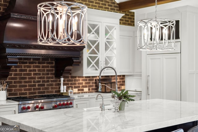 4874 Kettle River Pt, Suwanee, GA 30024 - kitchen with a chandelier, decorative backsplash, stove, and white cabinets
