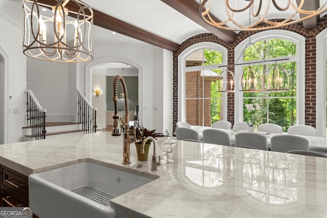 4874 Kettle River Pt, Suwanee, GA 30024 - kitchen view of a chandelier, light stone countertops, arched walkways, decorative light fixtures, and crown molding