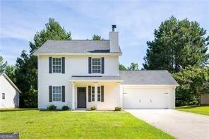 5484 Denny Dr, Atlanta, GA 30349 - view of front facade with driveway, a chimney, a garage, and a front yard